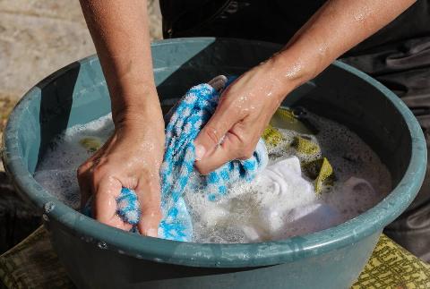 Clothes being washed by hand in a bucket. 