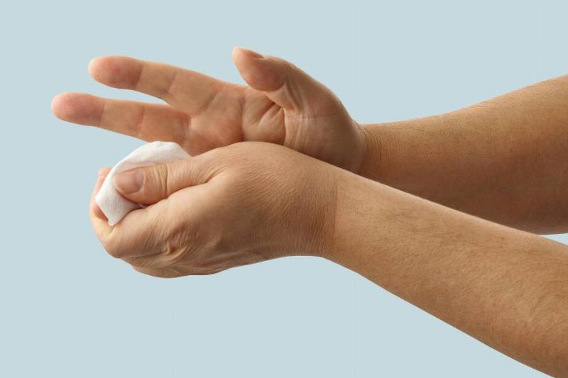 close up of person holding cotton pad to hand after cut