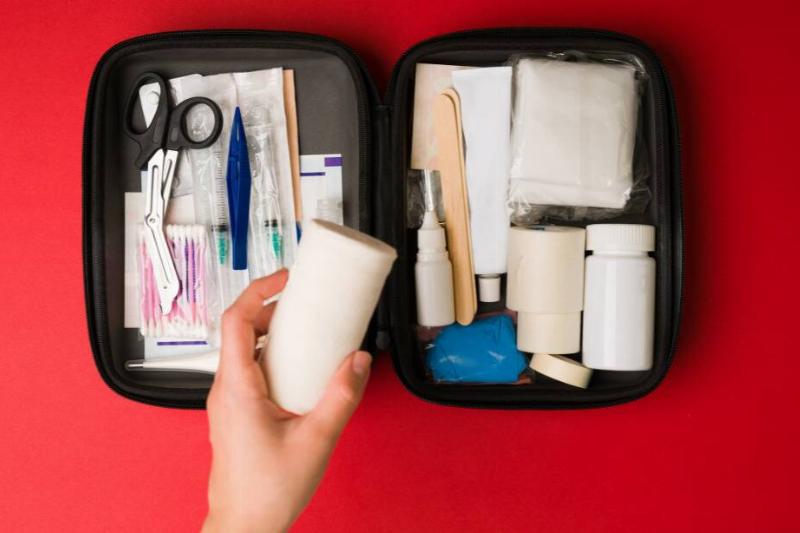 aerial shot of open first aid kit, with hand holding cotton gauze roll