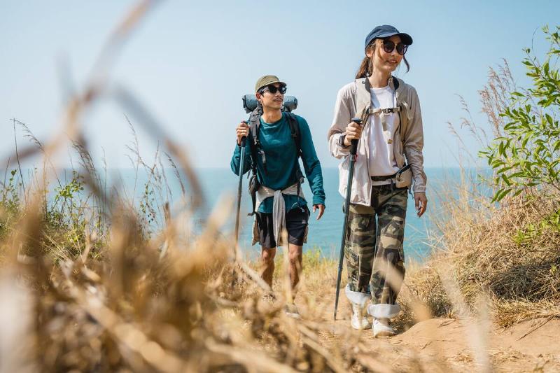 hiker couple on beach hiking trail, wearing sunglasses hats and layered sun protection clothing
