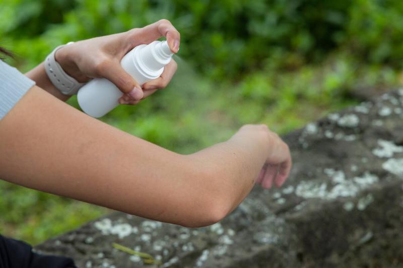 Woman apply mosquito repellent on arm