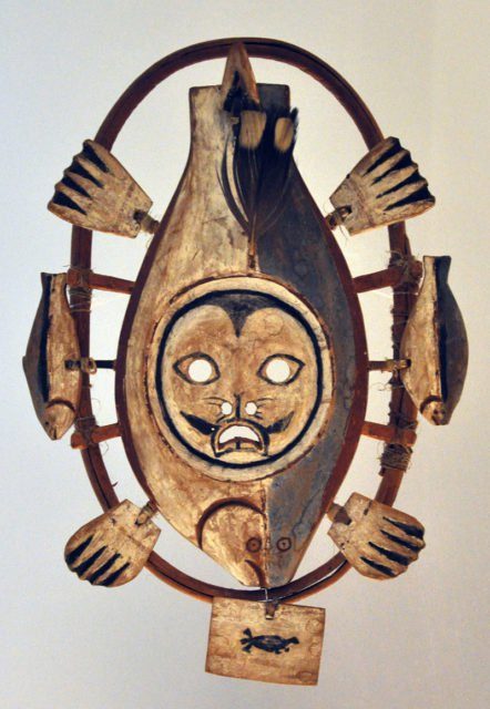 Wooden mask in the form of a flatfish, mounted on a wooden ring with wooden pegs tied to the ring with sinew.