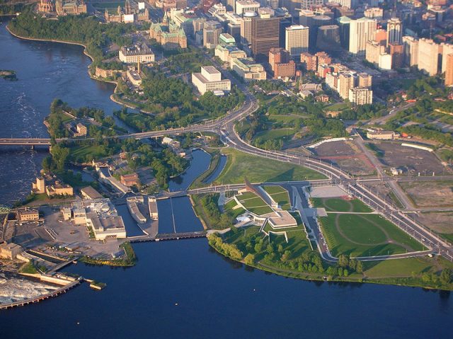 The Canadian War Museum, Lebreton Flats (under redevelopment), Victoria Island, the Portage Bridge and the Ottawa River, as viewed from a hot air balloon. Ottawa, Canada. – Author: Shanta Rohse – CC BY 2.0