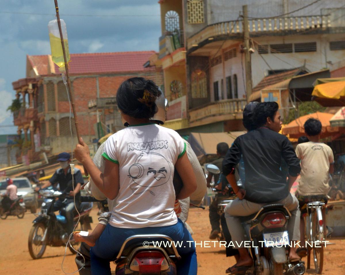 Motor bike medicine in Battambang carrying a drip for her baby.