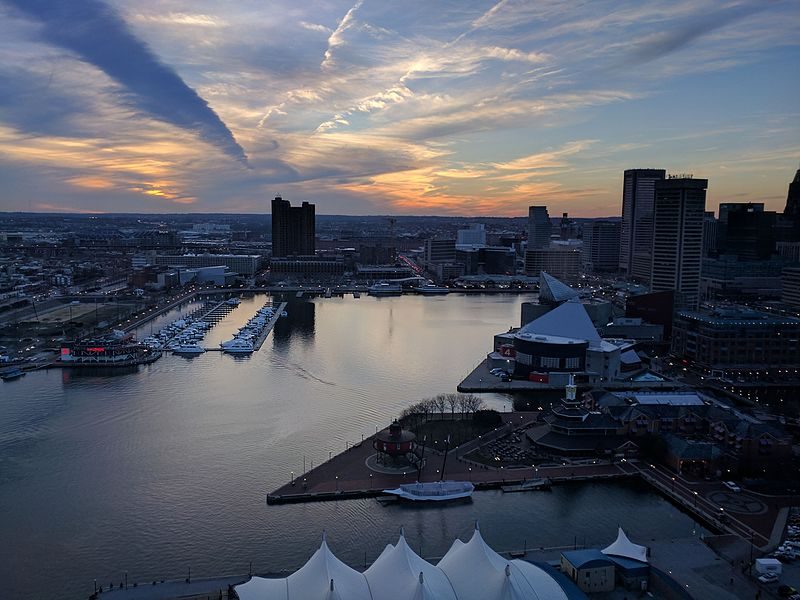 Sunset at Baltimore’s Inner Harbor, with the top of the Pier Six Pavilion visible in the foreground – Author: Dicklyon – CC BY-SA 4.0