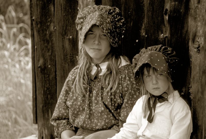 Young girls in early American pioneer clothing give a feel for what life might have been like.