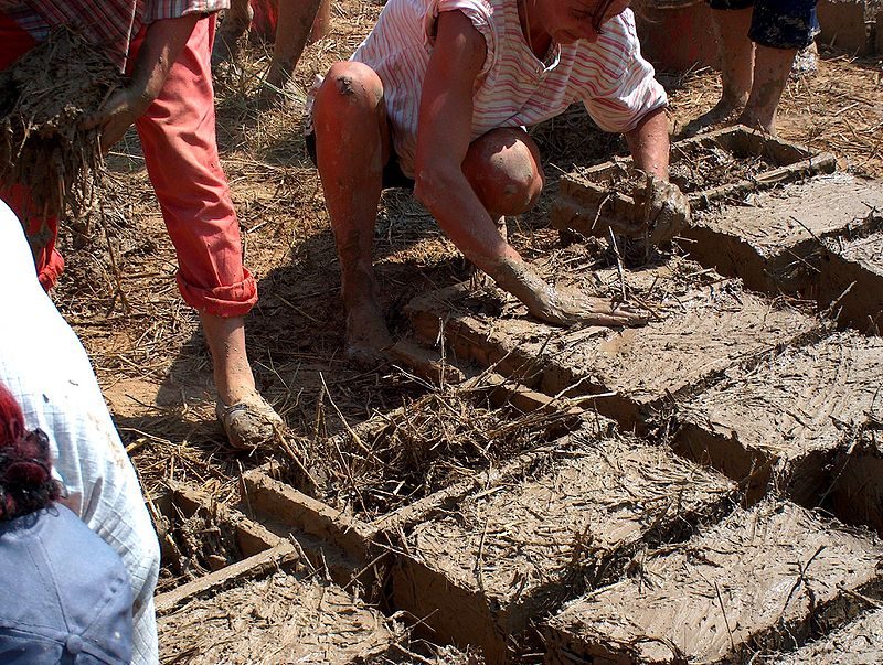 Mixing mud and straw in brick frames- Author: Soare – CC BY-SA 3.0