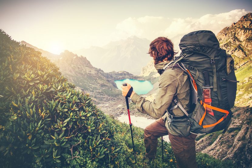 Man Traveler with big backpack mountaineering Travel Lifestyle concept lake and mountains on background Summer extreme vacations outdoor