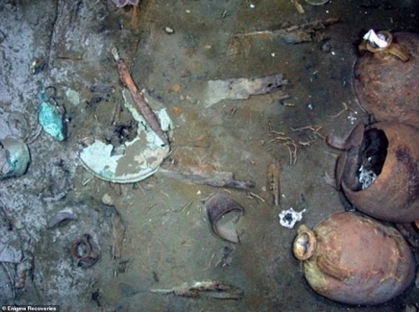 An iron sword and copper shield submerged in the mud to the top left of the image in one of the shipwrecks  ©Enigma Recoveries