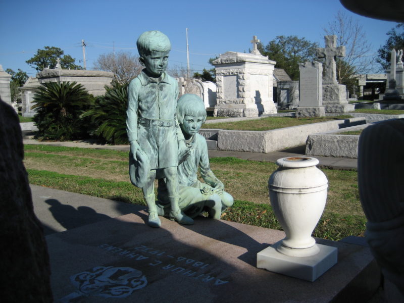 Statues of a young boy and girl standing before a stone vase