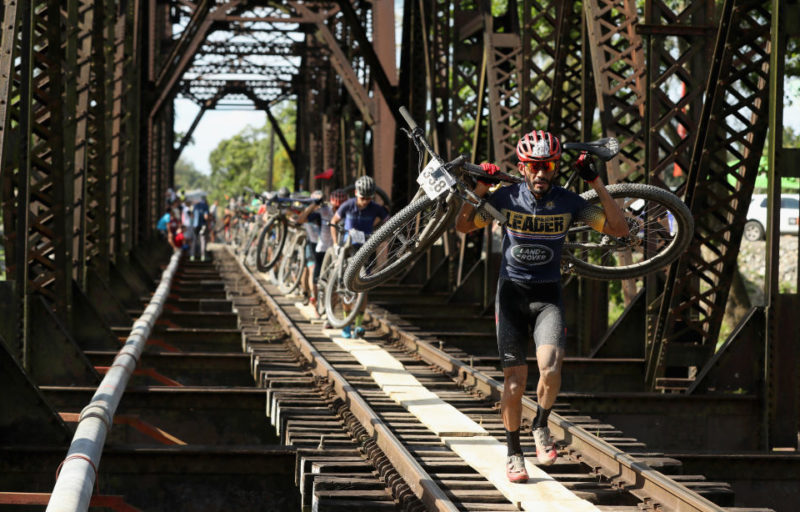 Cyclists carrying their bikes while crossing a bridge