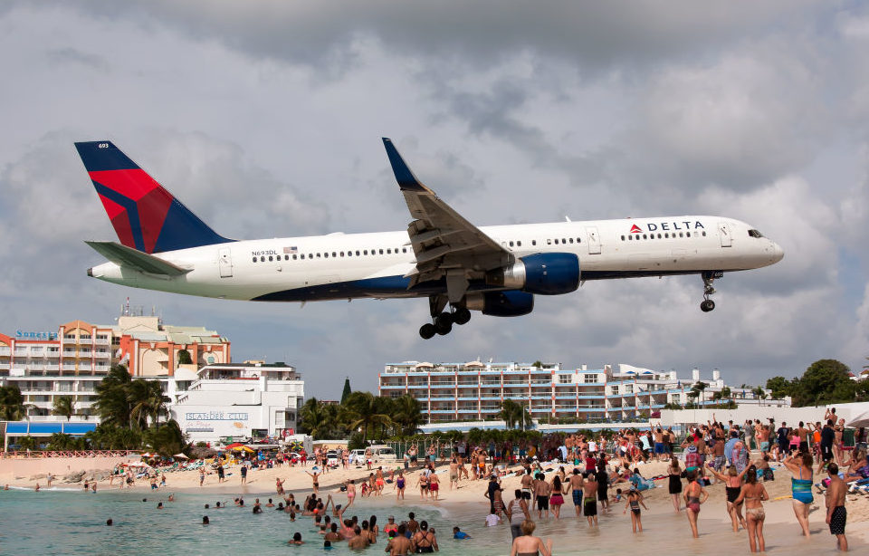 Airplane flying over a beach filled with people