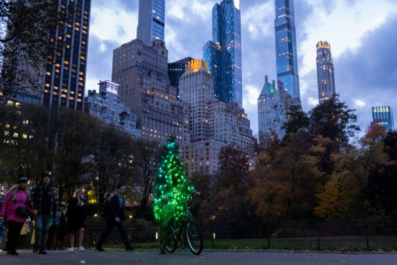 Man riding a bicycle while dressed as a Christmas tree.