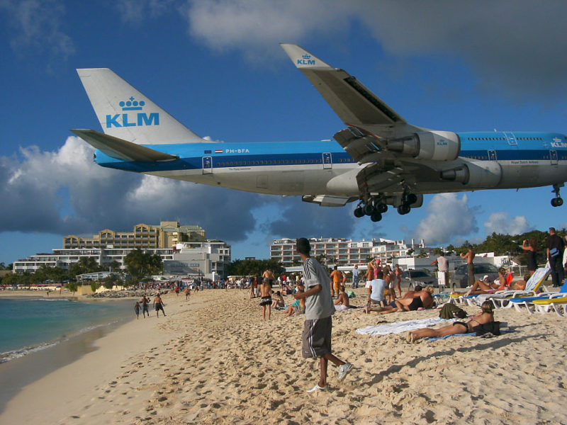 Airplane flying directly over a beach crowded with people