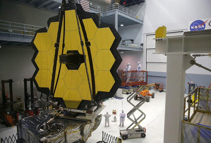 NASA engineers standing beneath the James Webb Space Telescope