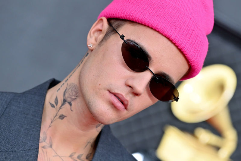 Justin Bieber wearing sunglasses and a pink beanie