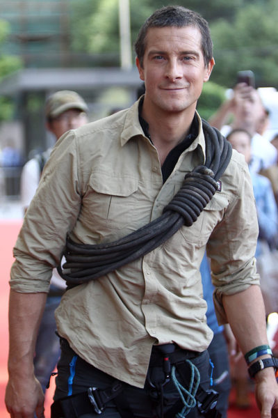 Bear Grylls standing with a rope tied diagonally across his chest