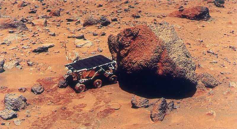 Sojourner rover parked beside a rock on the surface of Mars