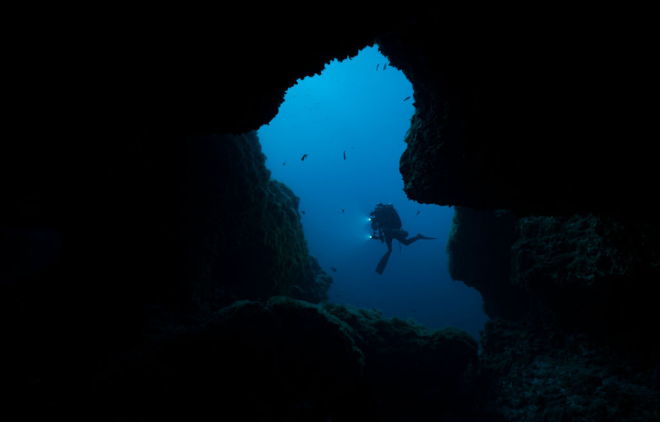 Diver swimming through a cave underwater