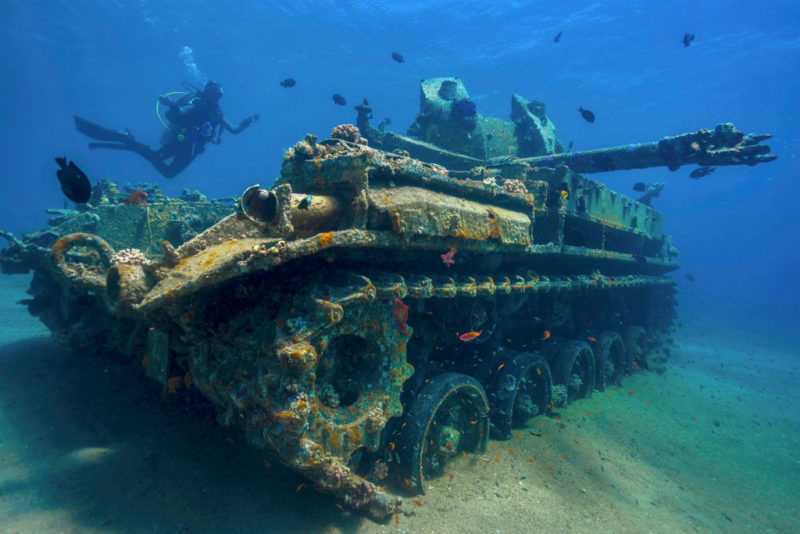 Diver swimming around a sunken military tank