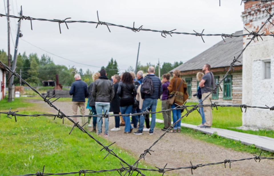 Group standing just beyond the barbed wire at Perm-36