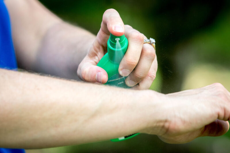 Woman applying bug spray to her skin