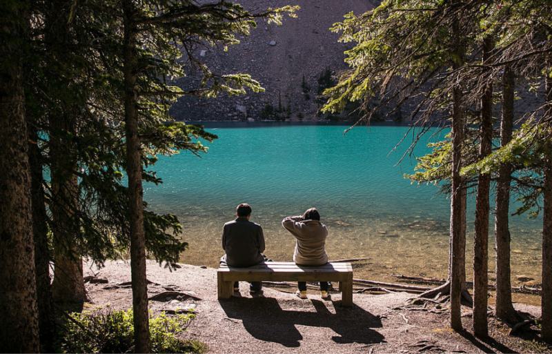 Two people sitting along the shore on Moraine Lake