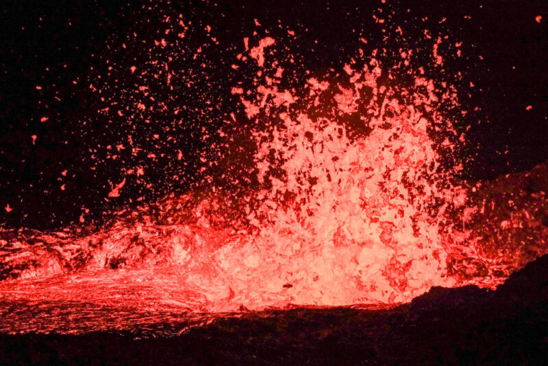 Molten lava being blasted into the air from a fissure in the ground